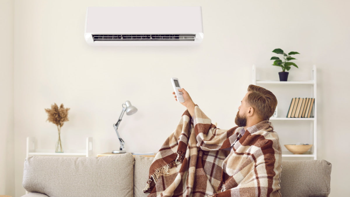 Man gebruikt airco warmtepomp als verwarming met een deken op de bank