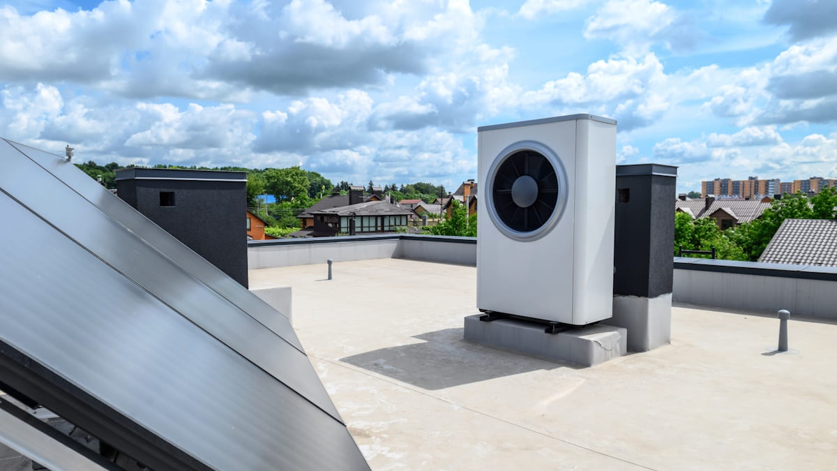 Een warmtepompsysteem op een plat dak tegen een bewolkte lucht.
