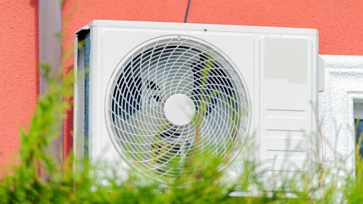 Buitenunit van hybride warmtepomp met gras op de voorgrond